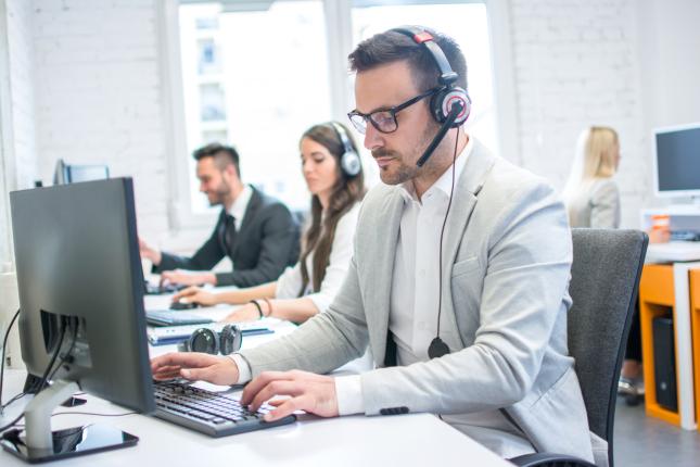 Support agents working on computers with headsets 