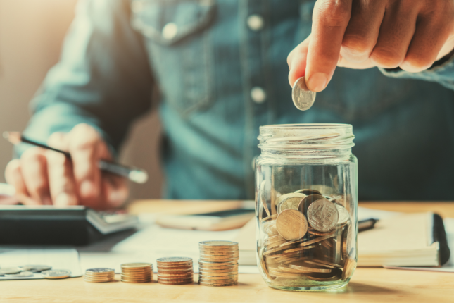 man putting money into a savings jar